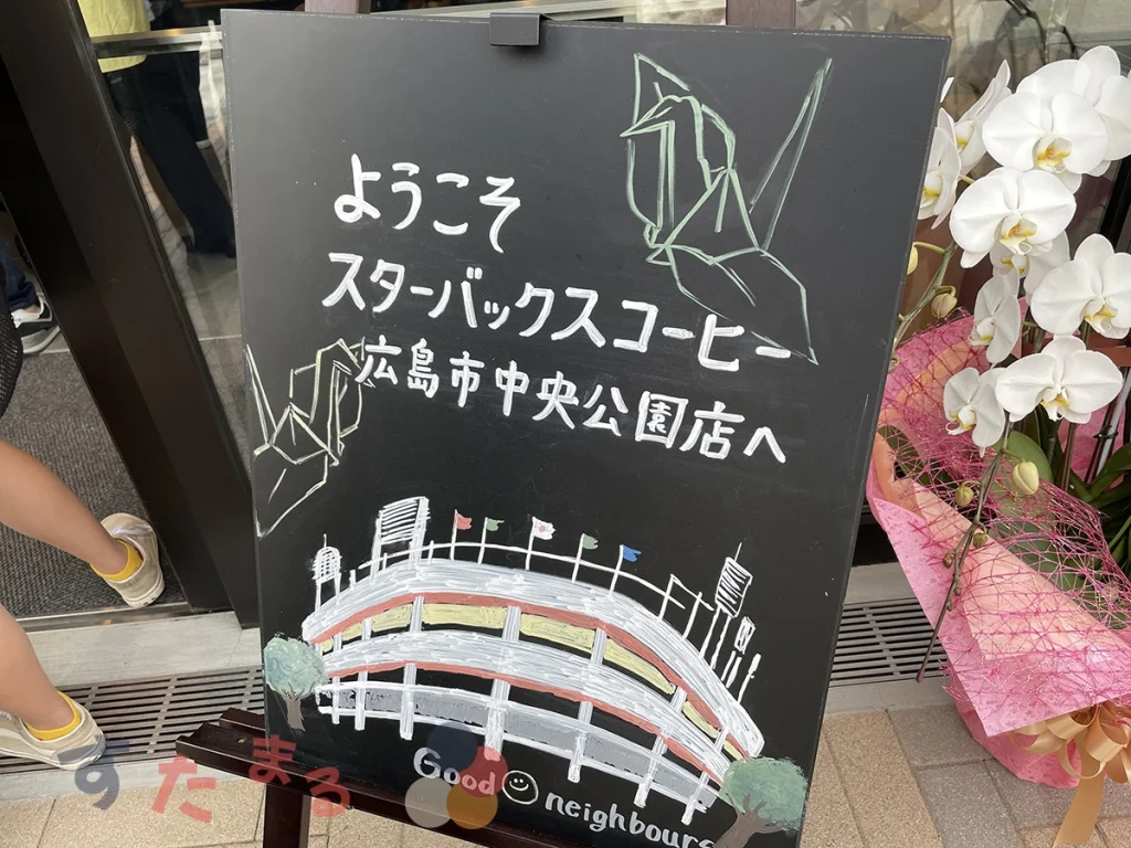 スターバックスコーヒー 広島市中央公園店の折り鶴と球場が描かれたウェルカムボードの写真