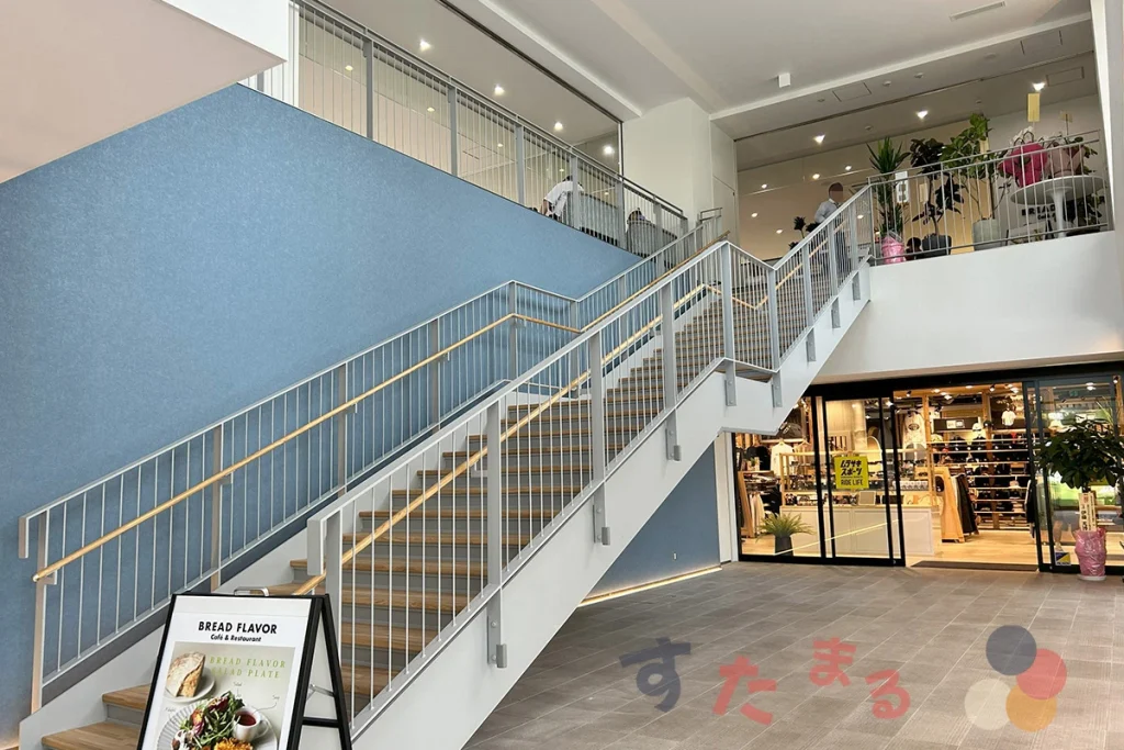 A棟のムラサキスポーツ (１階) とブレッドフレーバー (２階)とそれらを繋ぐ階段の写真