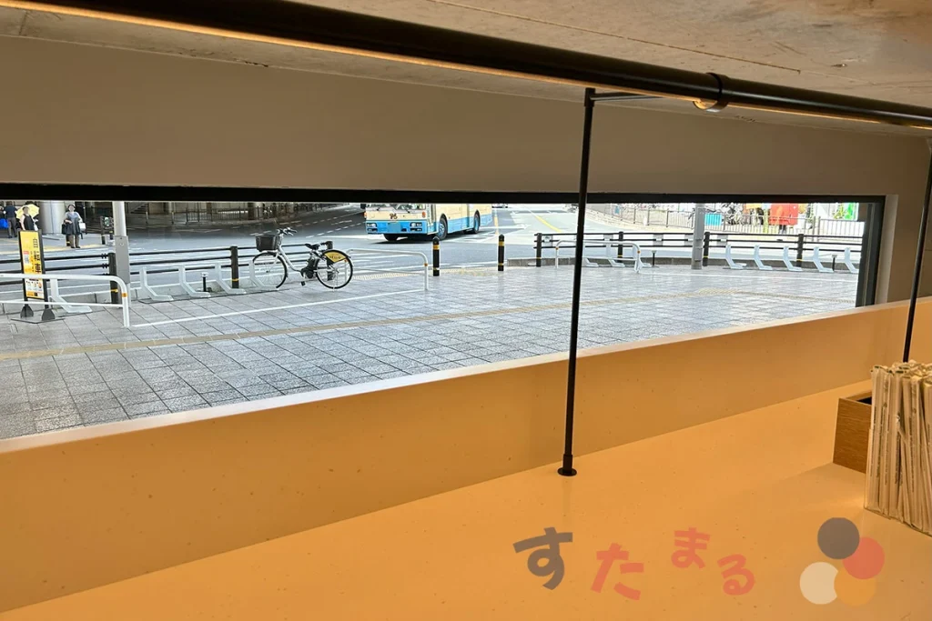 スターバックスコーヒー 阪急豊中駅前店のストローやガムシロップ、フレッシュが置いてある台の上にある小窓から見える豊中駅南側の高架下の交差点のようす写真